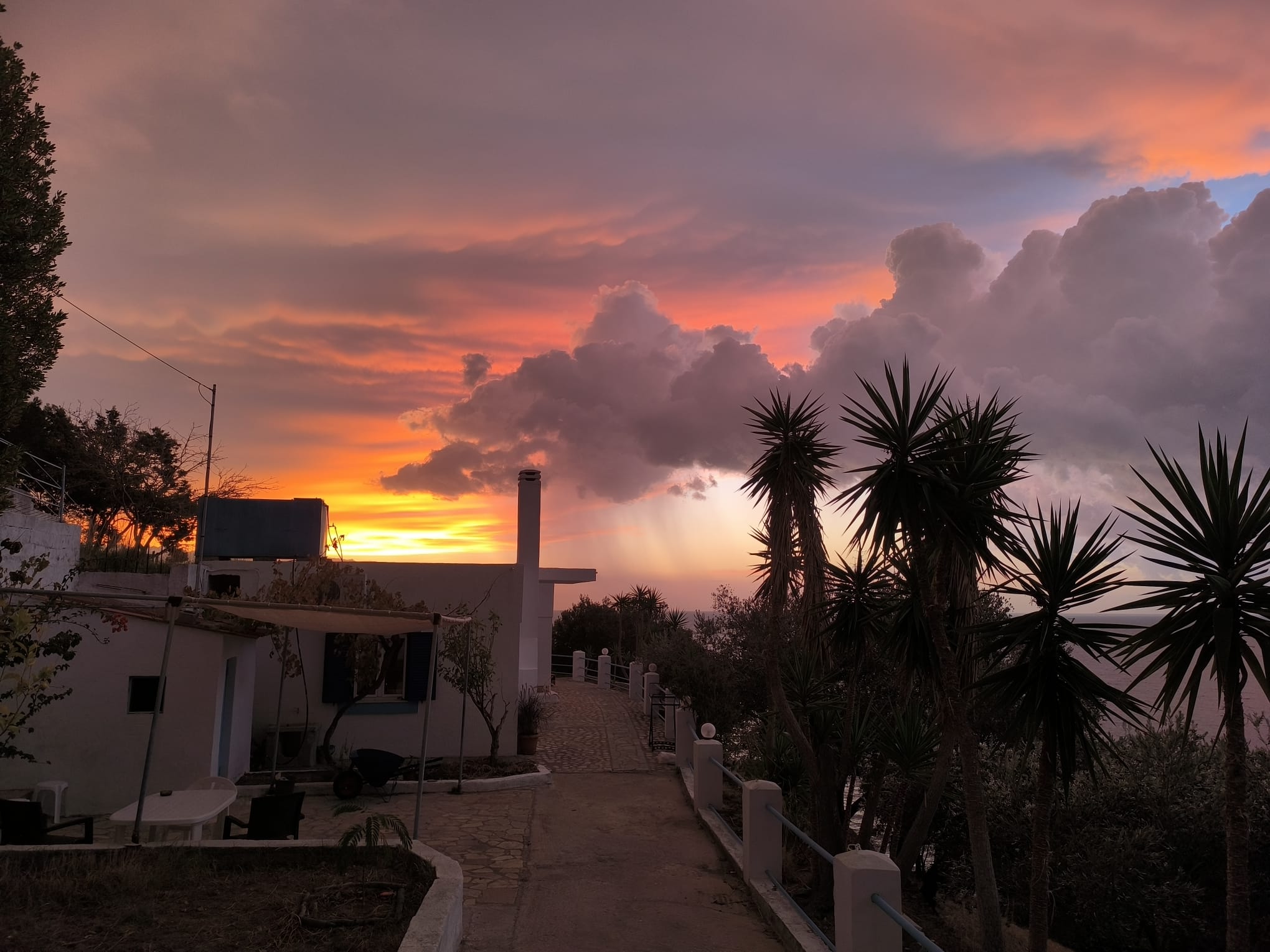 A house beneath a dramatic sunset cloud, photographed by Myrte